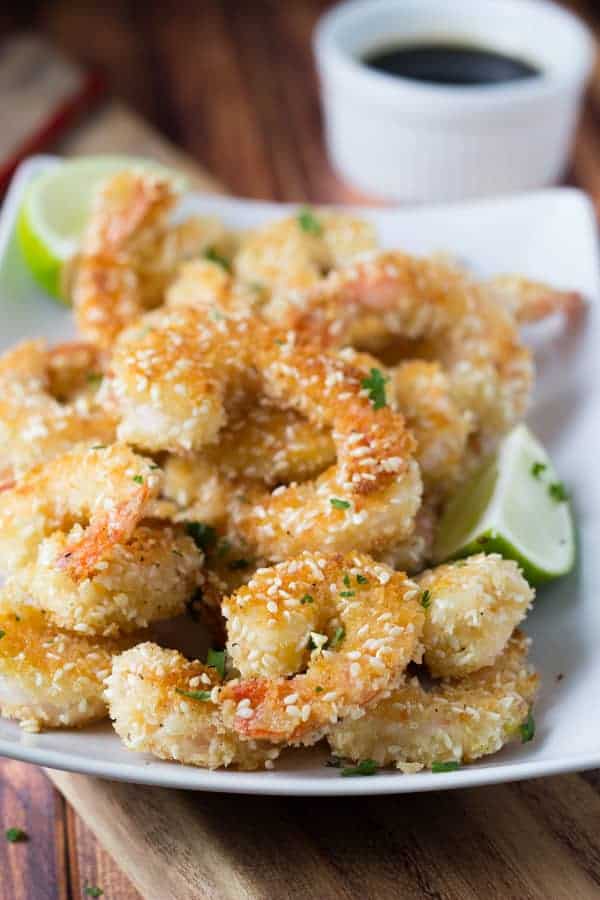 plate full of crispy sesame shrimp with dipping sauce in background