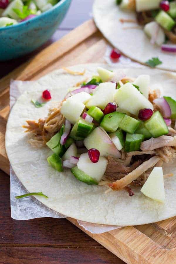 tortilla topped with apple cider carnitas and fresh apple salsa on wooden cutting board