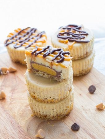 stack of mini peanut butter cup cheesecakes with a pretzel crust on wood board
