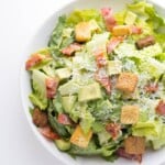 overhead shot of avocado caesar salad in white bowl