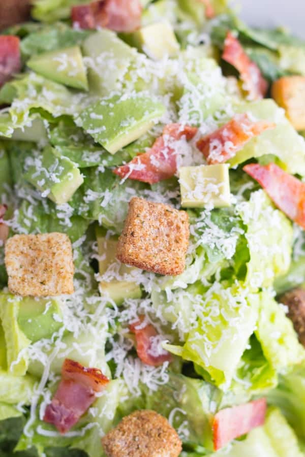 close up shot of croutons, bacon and avocado cubes in the avocado caesar salad 
