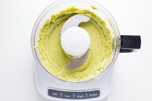 overhead view of food processor containing avocado caesar salad dressing after blending