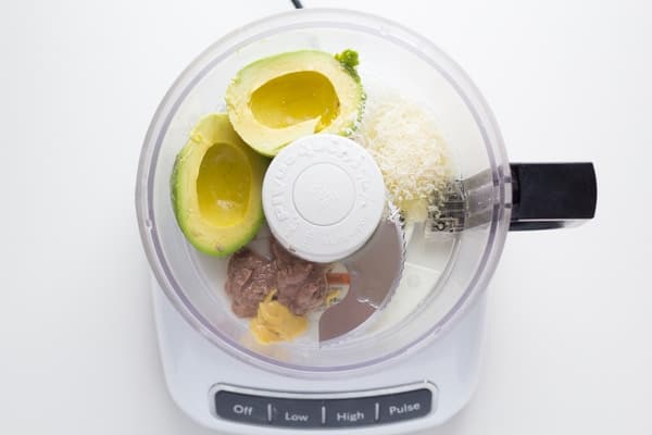 overhead view of food processor with avocado caesar salad dressing ingredients