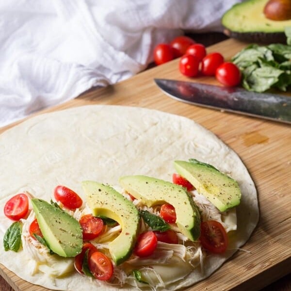 chicken and avocado caprese quesadillas on wood board with knife in background