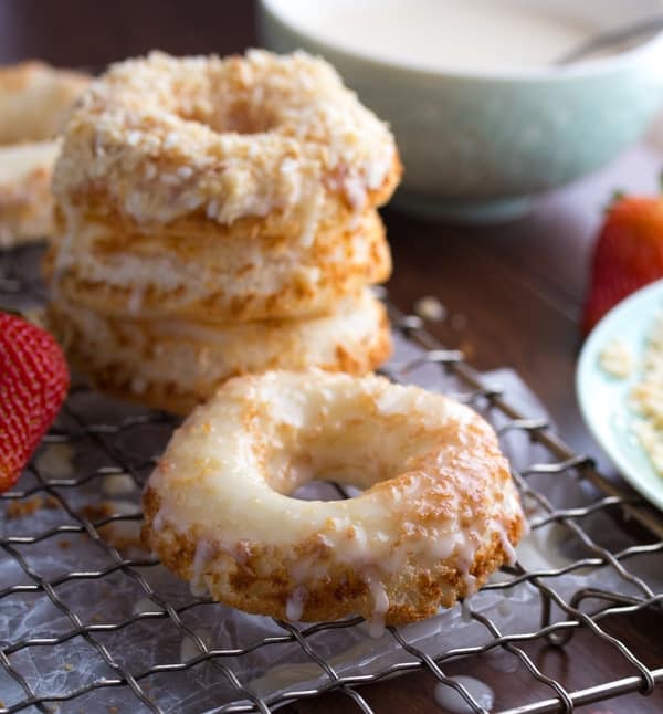 glazed angel food cake donut with stack of three donuts and bowl of glaze in the background