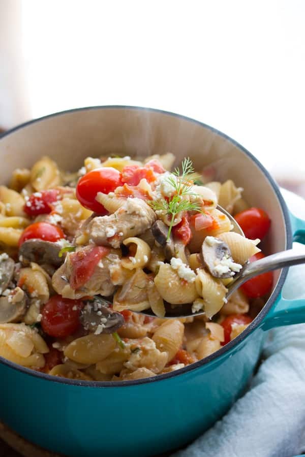 spoon scooping the one pot pasta with chicken + feta out of a blue pot