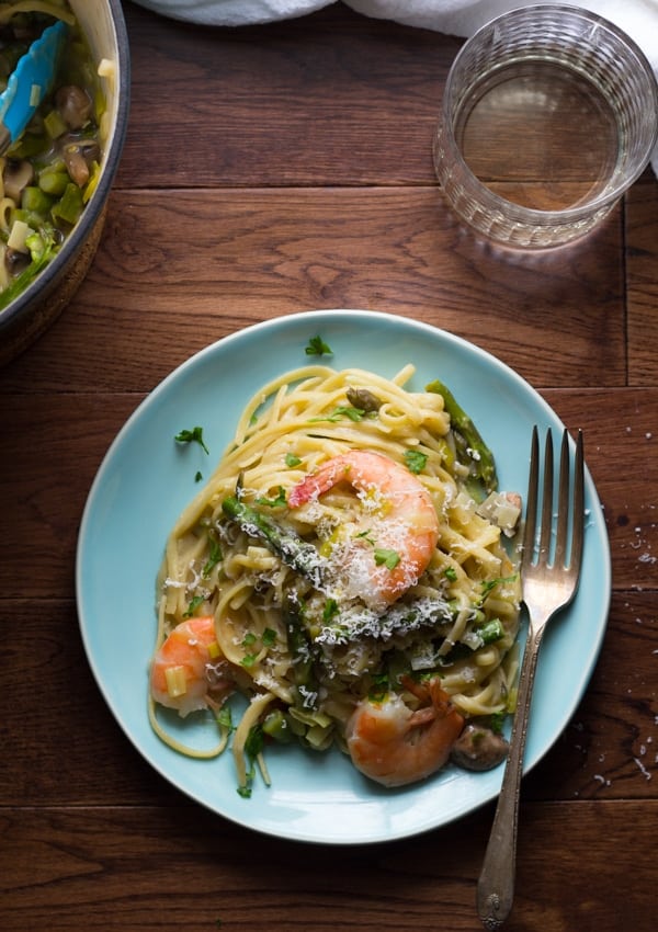 shrimp linguine with spring vegetables on blue plate with fork