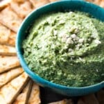 spinach artichoke whipped feta dip in blue bowl with pitas around it