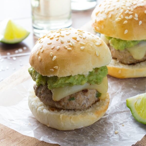 two tequila turkey sliders with guacamole on parchment with limes