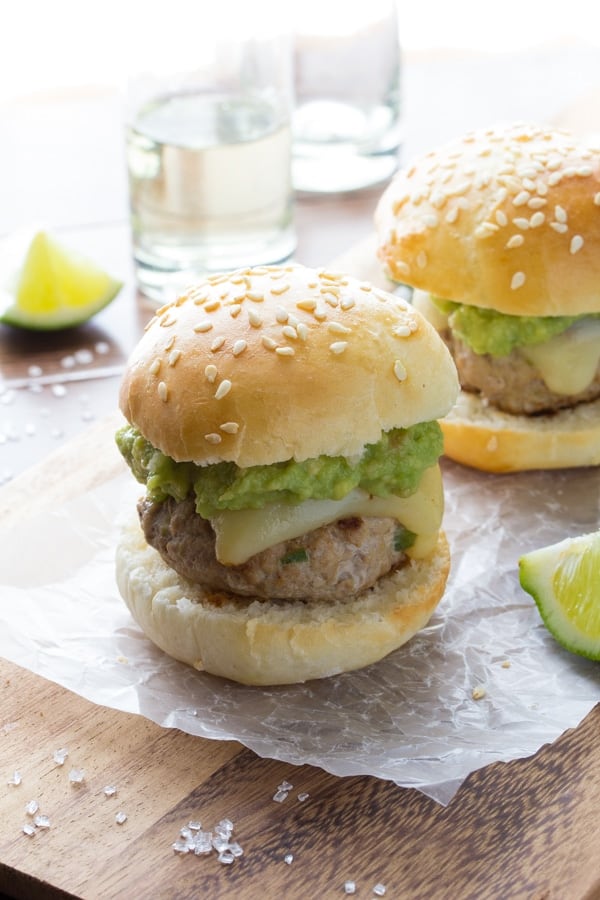 two tequila turkey sliders on cutting board with shots of tequila in the background