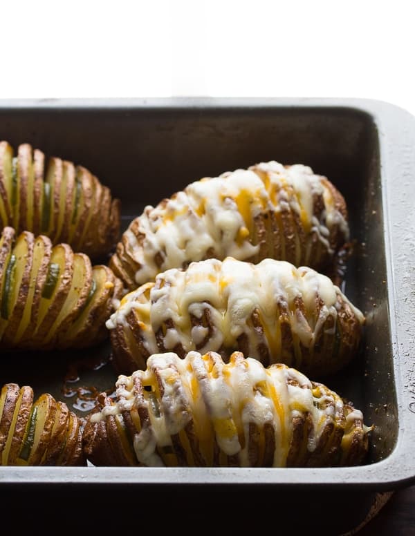 hasselback potatoes stuffed with jalapeno slices and covered in melted cheese in baking dish