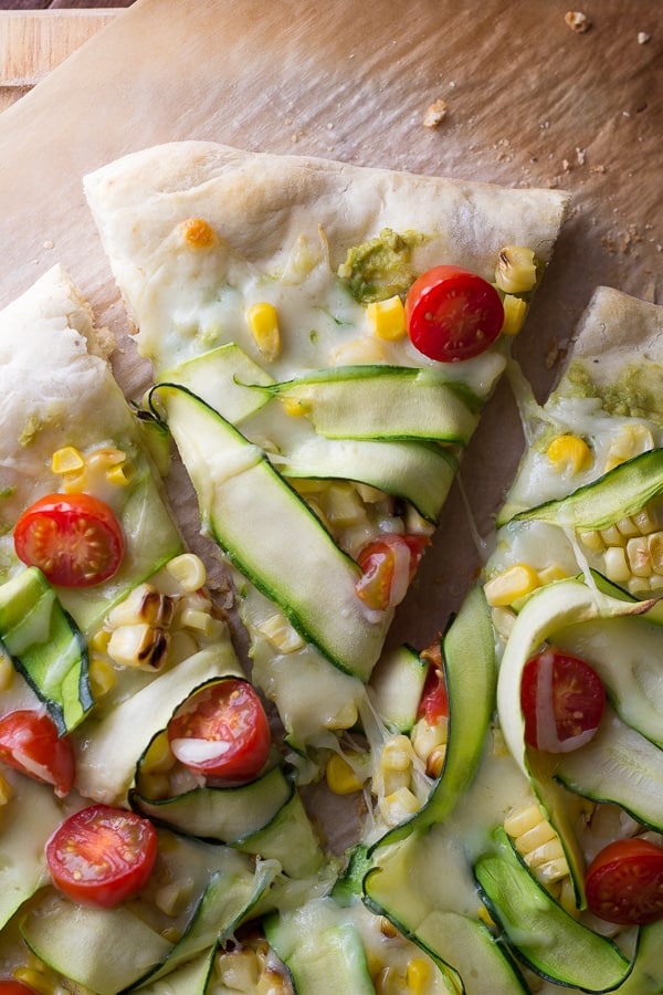 close up of a slice of guacamole pizza with a gooey cheese string