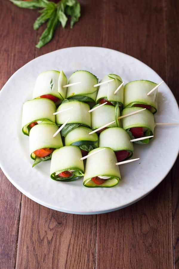 Overhead shot of zucchini roll ups on a white plate with toothpicks