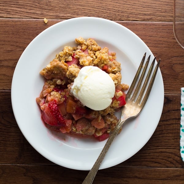 strawberry rhubarb crisp on plate with a scoop of ice cream and a fork