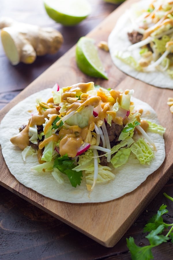 Ginger beef tacos with Peanut Sauce on wood serving board