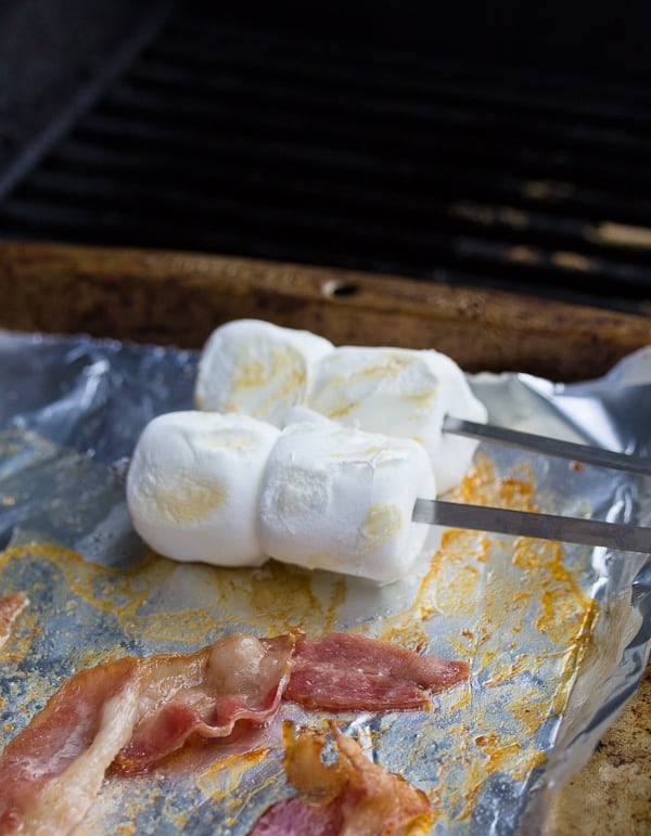 cooking the bacon and marshmallows on a foil-lined baking sheet placed on the grill