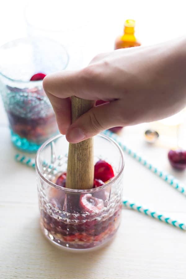 muddling the cherries and bourbon to make the cherry cocktail