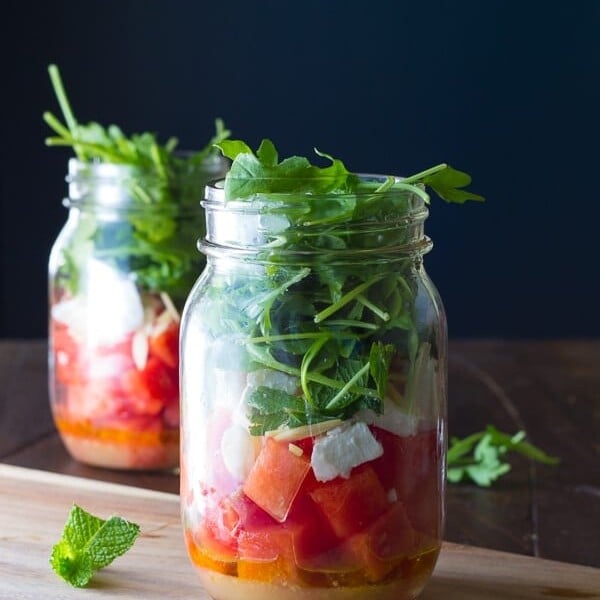 two mason jars with watermelon feta and arugula salad