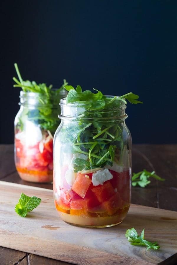 two mason jars with watermelon feta and arugula salad