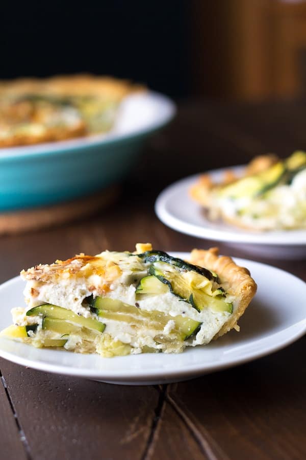 side angle view of zucchini ricotta quiche on plate with pie plate in background