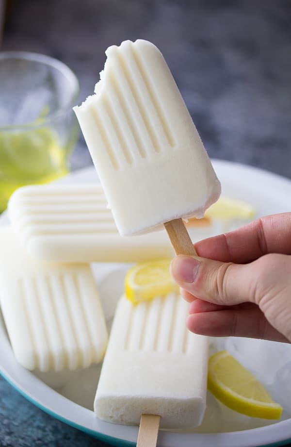 hand holding a limoncello popsicle with a bite taken out of it
