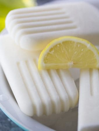 close up shot of creamy coconut limoncello popsicles with lemon slice