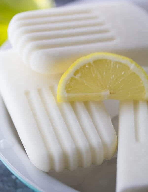 close up shot of creamy coconut limoncello popsicles with lemon slice