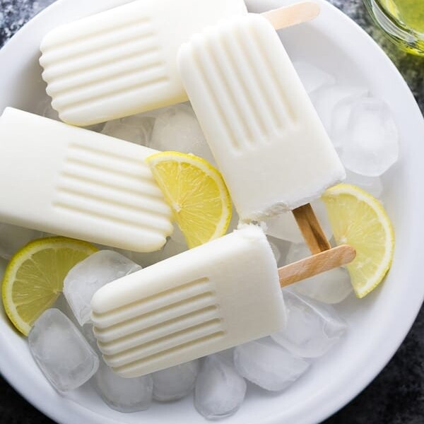 four creamy coconut limoncello popsicles in bowl with lemon slices