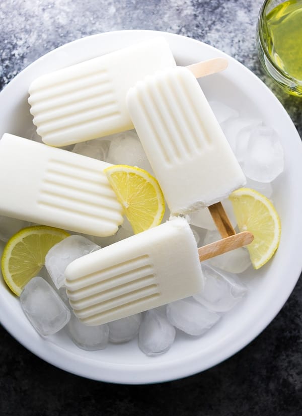 4 limoncello coconut popsicles in a bowl of ice cubes