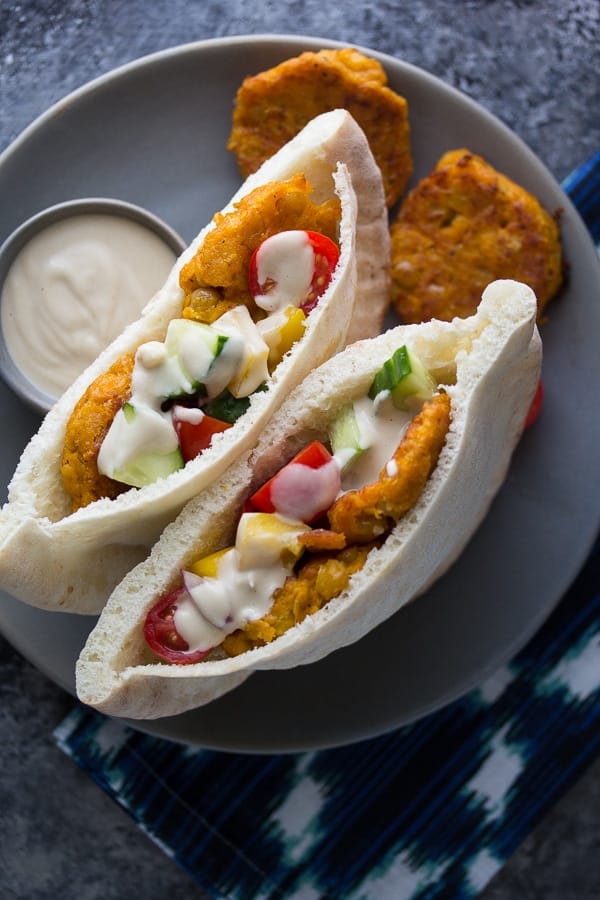 overhead view of sweet potato falafels in two pitas with salad and tahini sauce