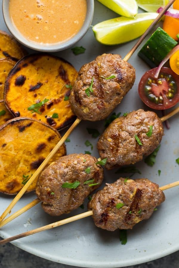 thai curry beef koftas with coconut sauce on gray plate with sweet potatoes and tomatoes
