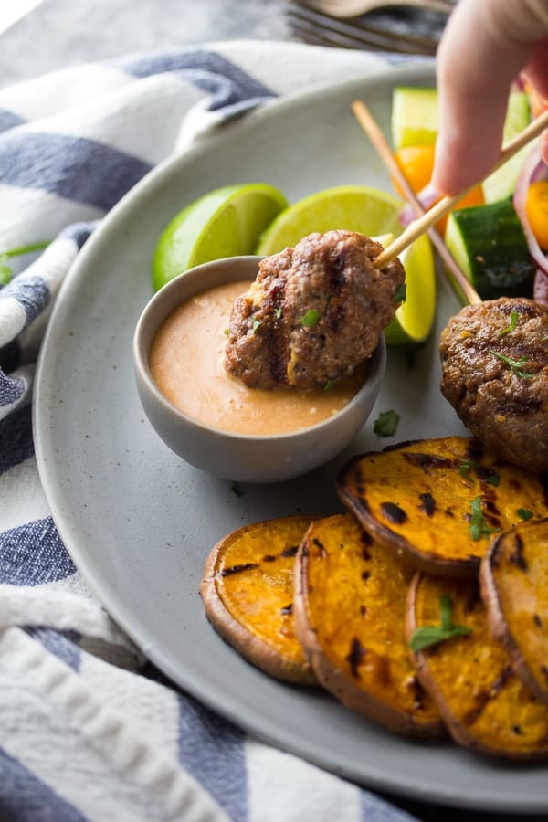 dipping a thai beef kofta kebab into the coconut dipping sauce