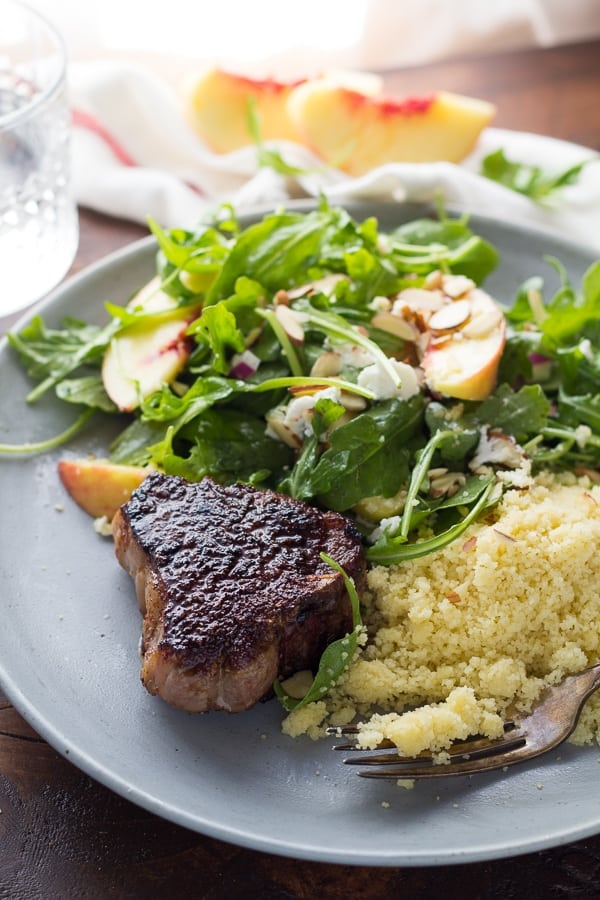 cooked lamb chop on plate with salad and couscous