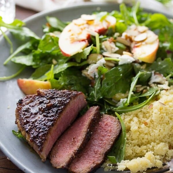 Chili brown sugar lamb chops with peach arugula salad on gray plate