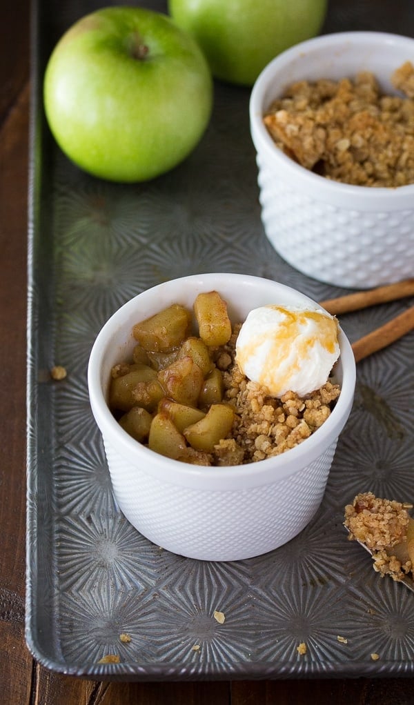 single serving apple crisp on baking sheet with scoop of ice cream on top