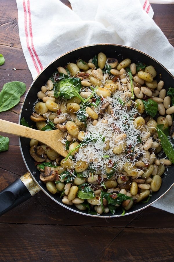 Overhead view of Gnocchi With Sundried Tomatoes and White Beans in skillet with grated parmesan on top