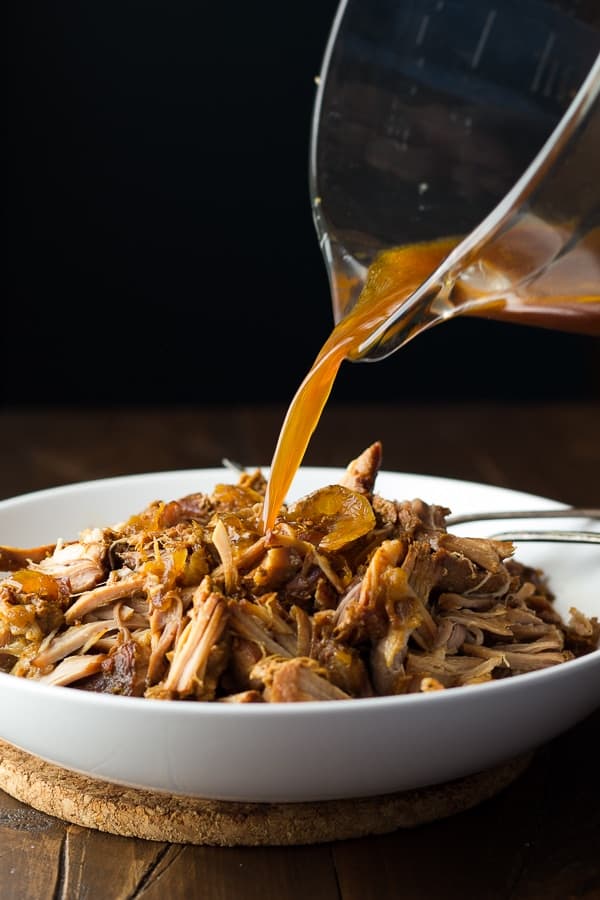 pouring cooking liquid over the slow cooker pulled pork