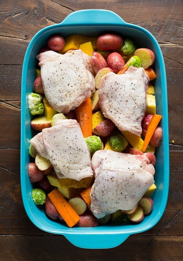 overhead view of roasted chicken and vegetables with honey miso butter in blue baking dish- before baking