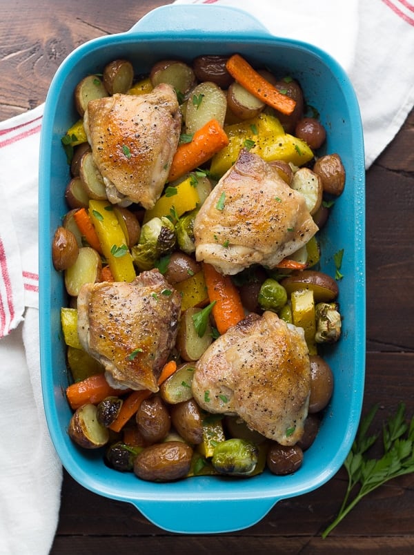 overhead view of roasted chicken and vegetables with honey miso butter in blue baking dish- after baking