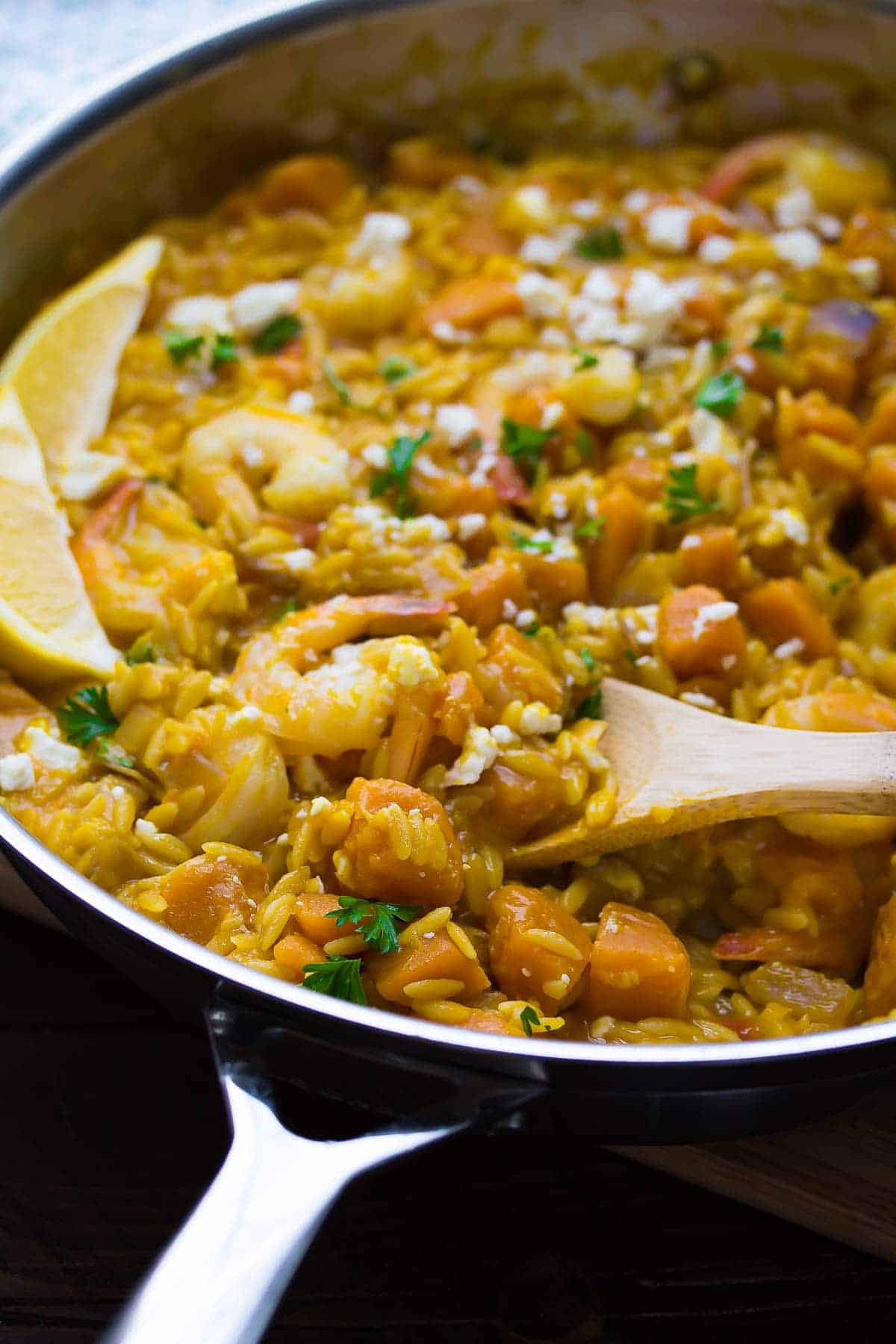 shrimp and squash orzo in silver pan with wooden spoon