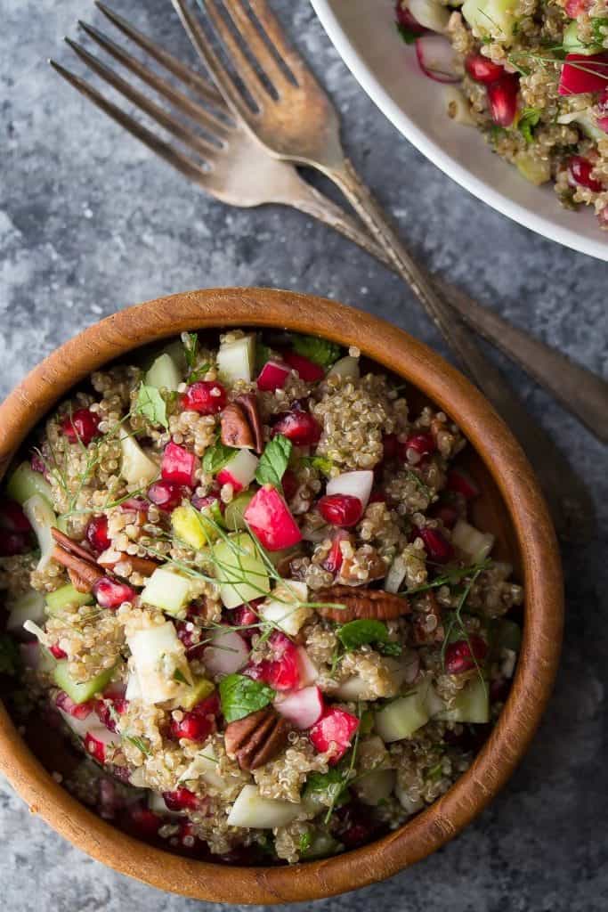 overhead shot of pomegranate fennel quinoa salad in wood bowl with forks