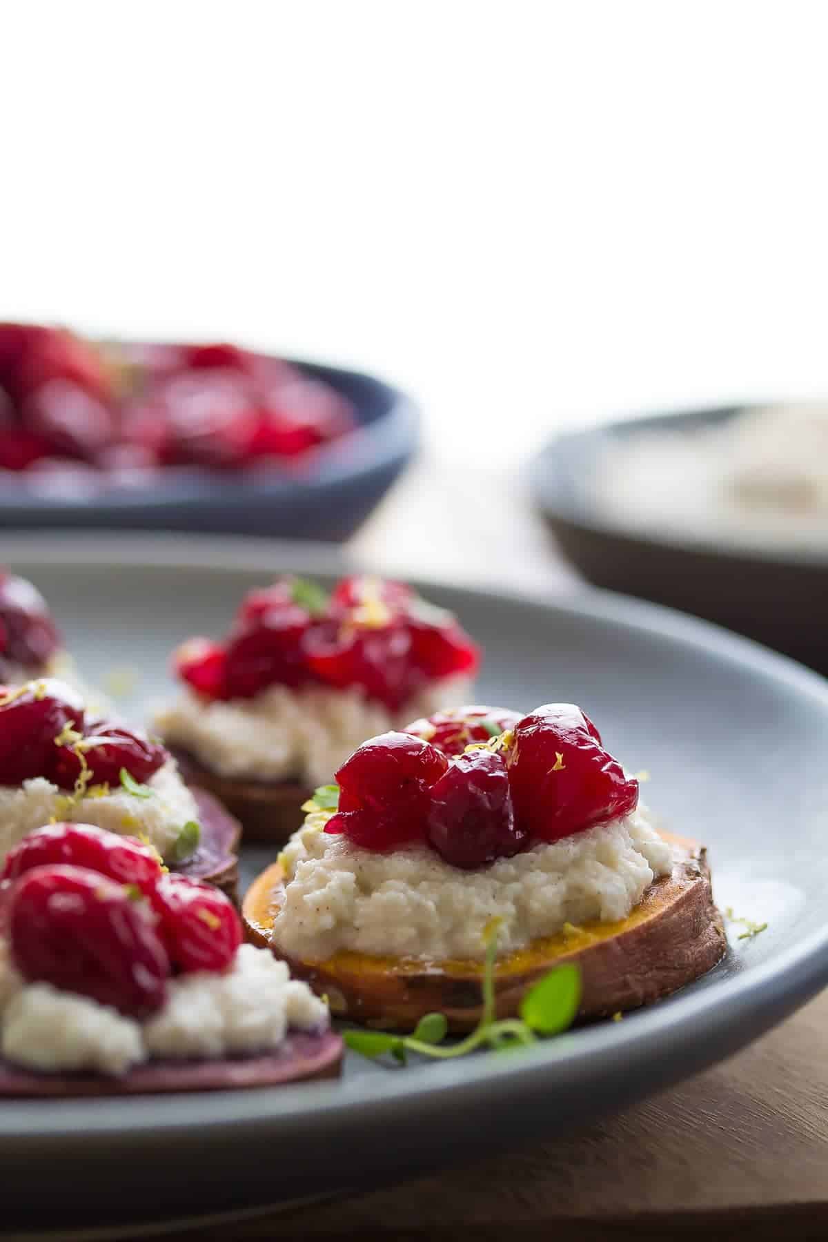 side angle of a sweet potato crostini topped with spiced ricotta and roasted cranberries