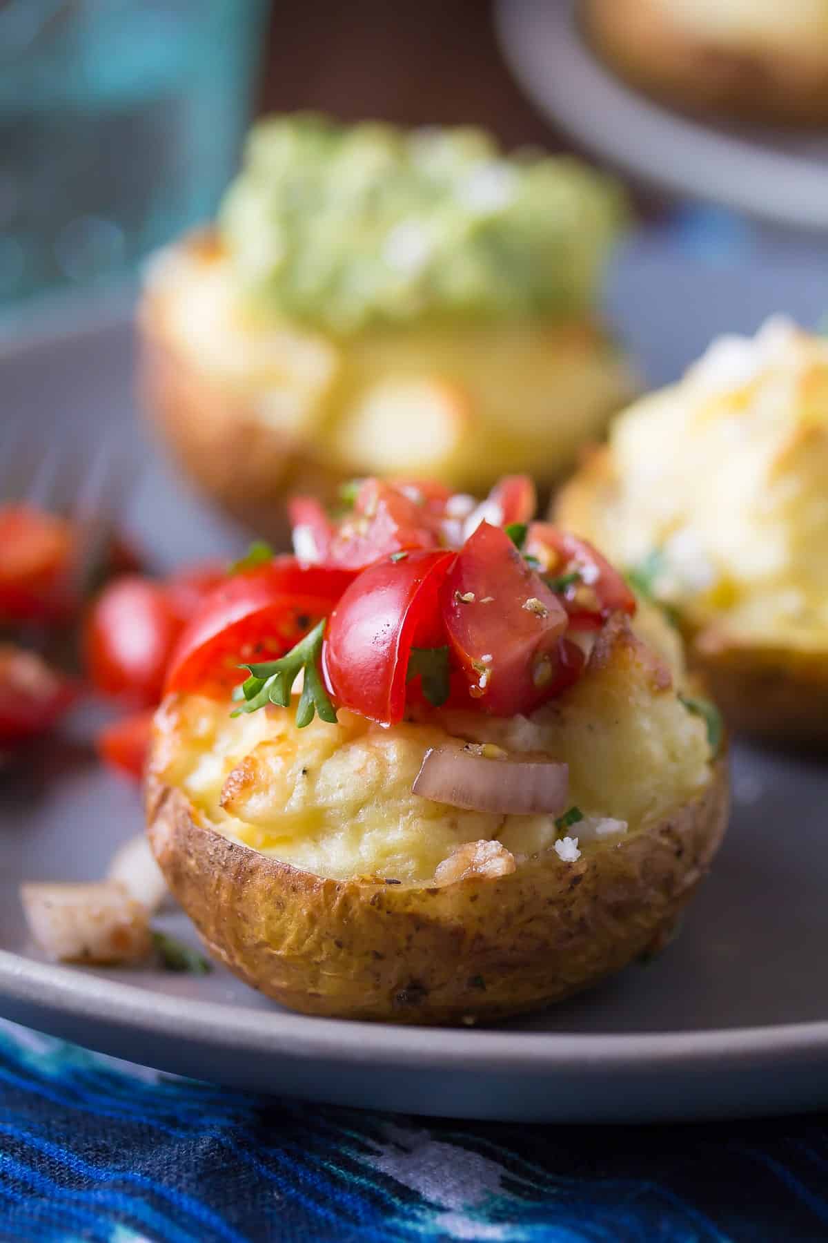 close up view of a twice baked breakfast potato topped with tomatoes