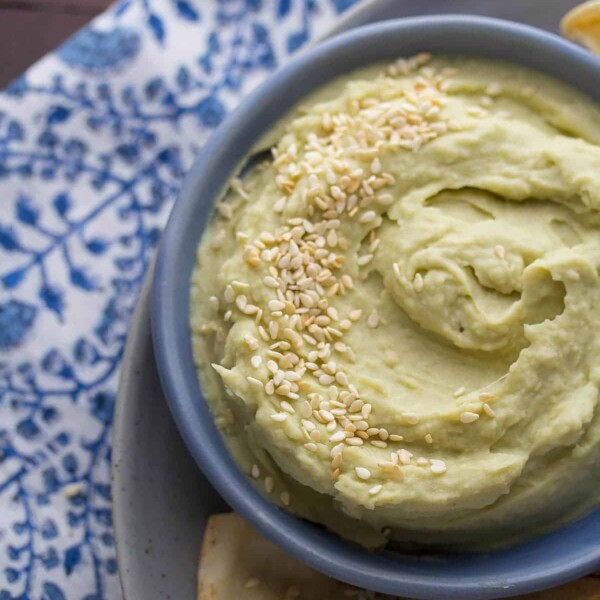 overhead shot of avocado wasabi dip with sesame pita chips in blue bowl