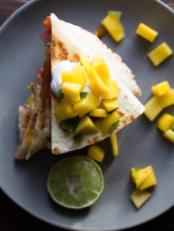 overhead shot of jamaican shrimp quesadillas with mango salsa on gray plate