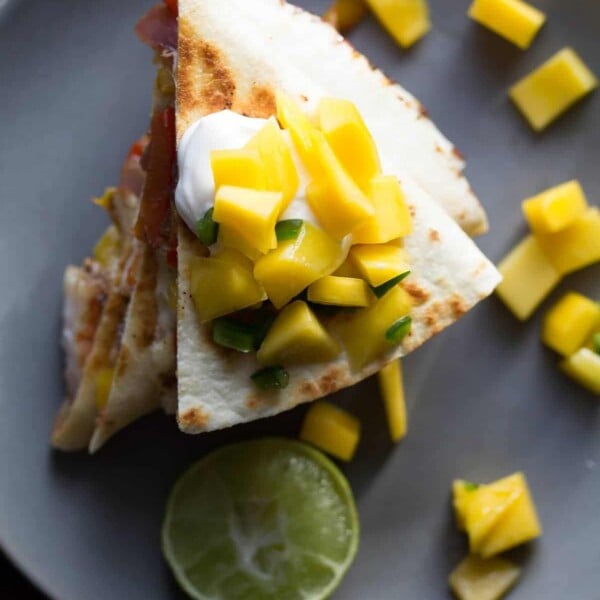 overhead shot of jamaican shrimp quesadillas with mango salsa on gray plate