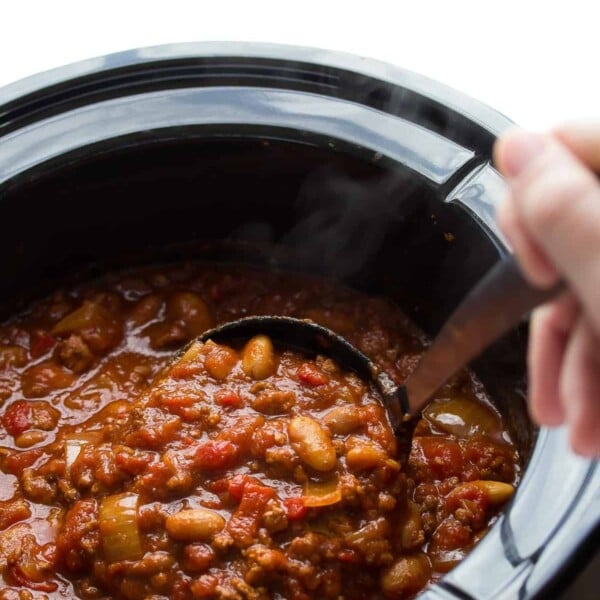 hand stirring roasted red pepper chili in the crock pot