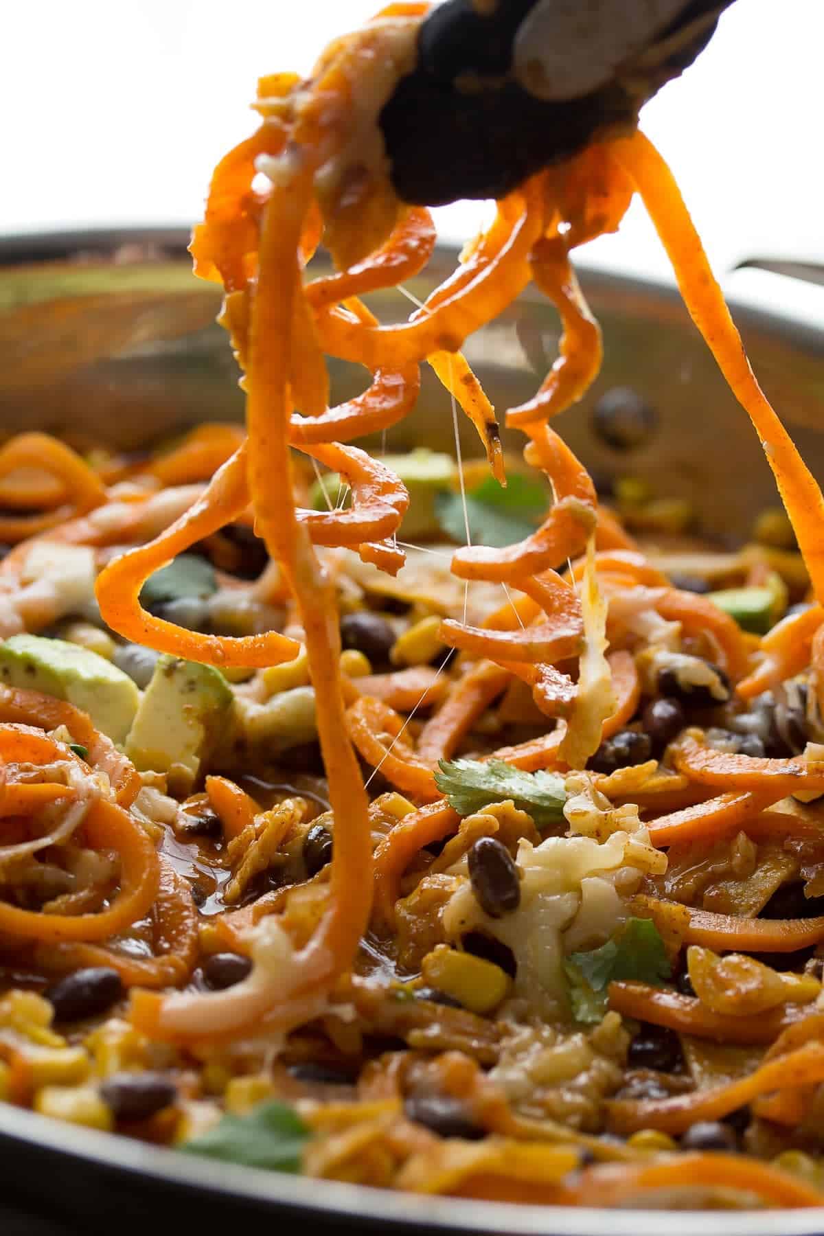 tongs lifting sweet potato noodles out of skillet