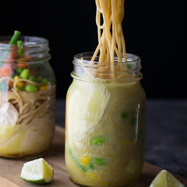 two mason jars with thai coconut instant noodles and lime wedges