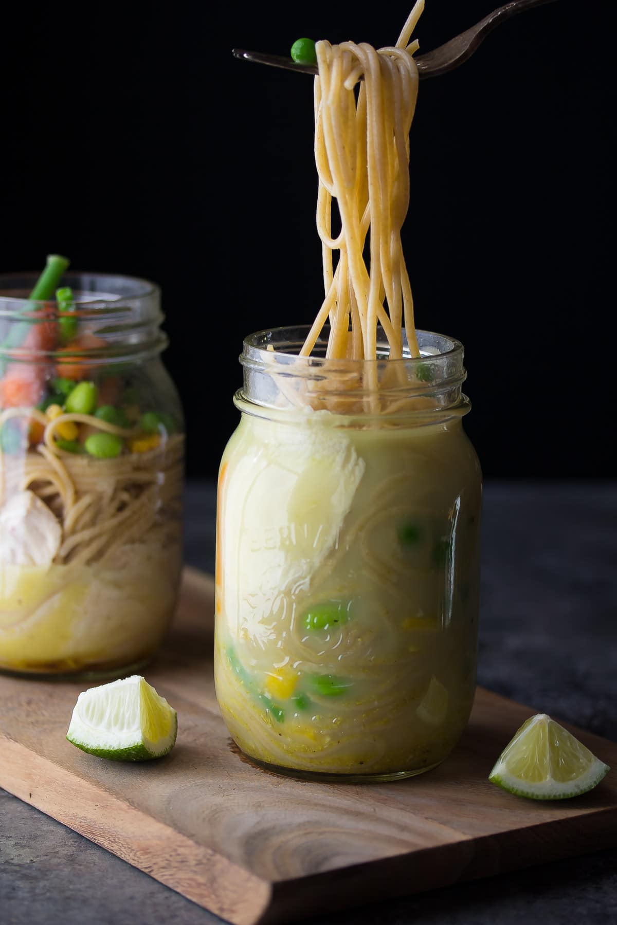 fork pulling pasta out of instant noodle jars